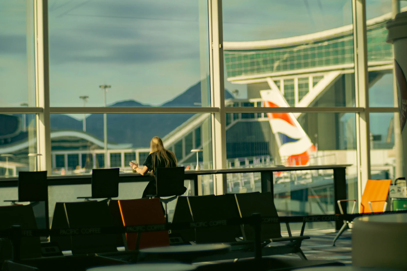 Woman seated at an airport gate looking at her phone