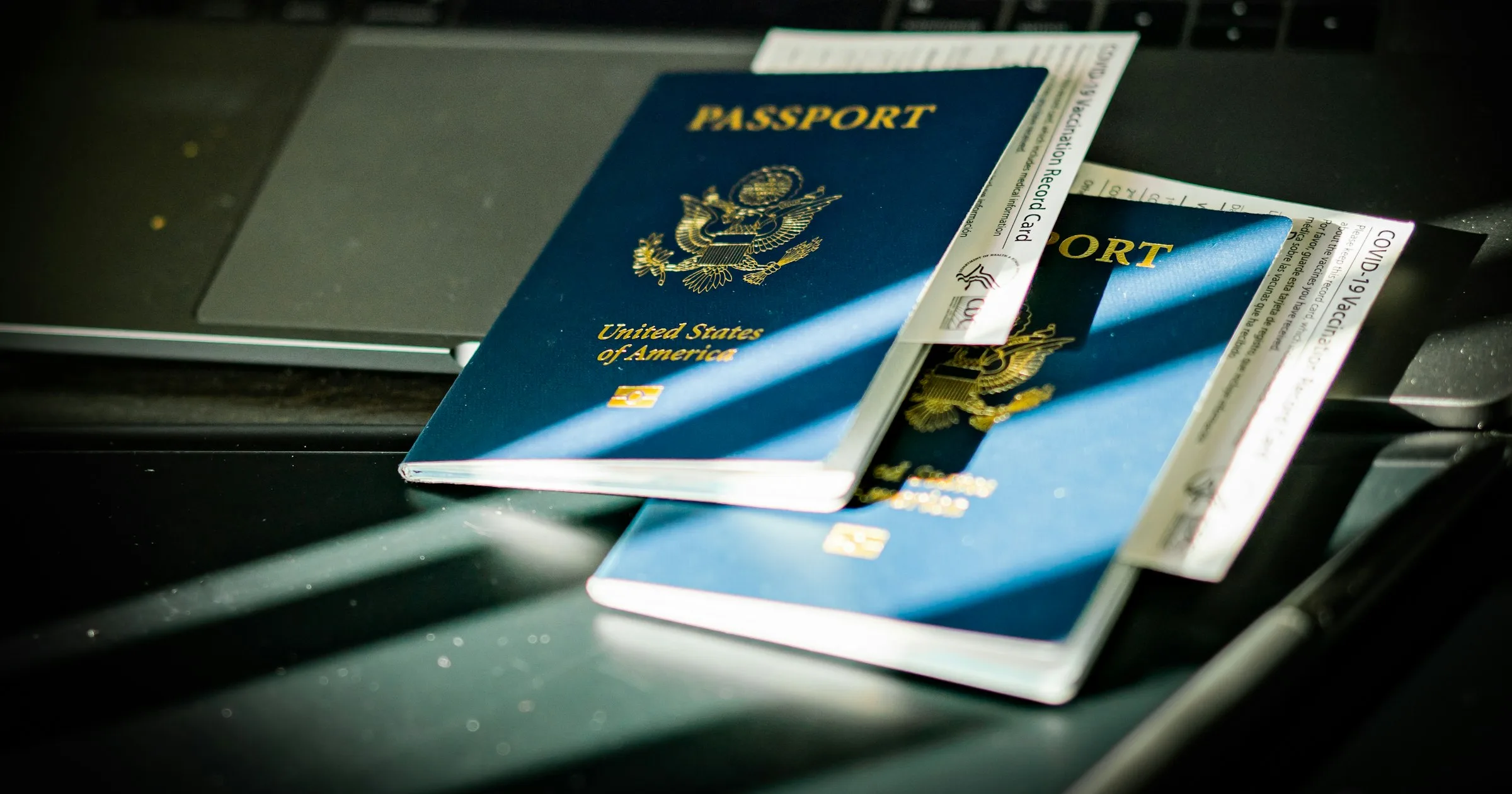 Two passports with boarding passes resting on a laptop keyboard