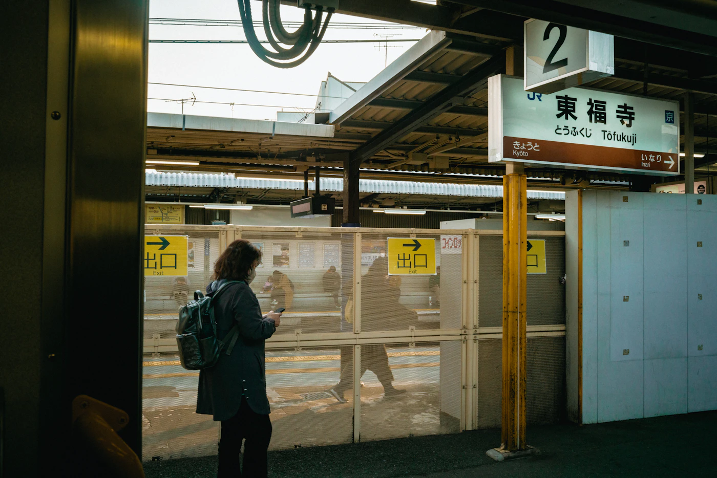 Traveller checking a smartphone on a railway platform in Japan