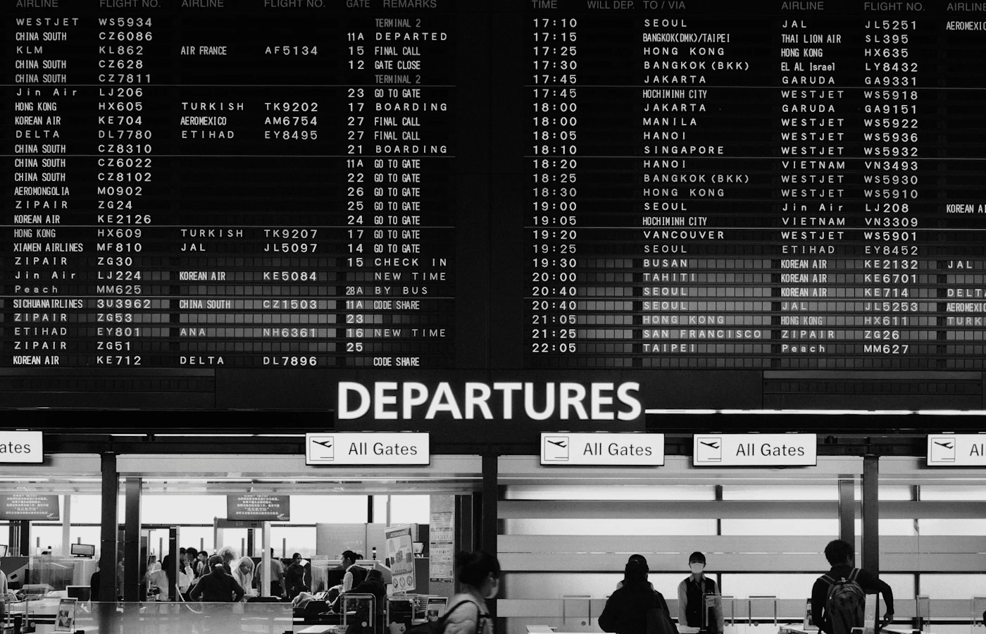 Travellers passing flight information boards at Narita Airport